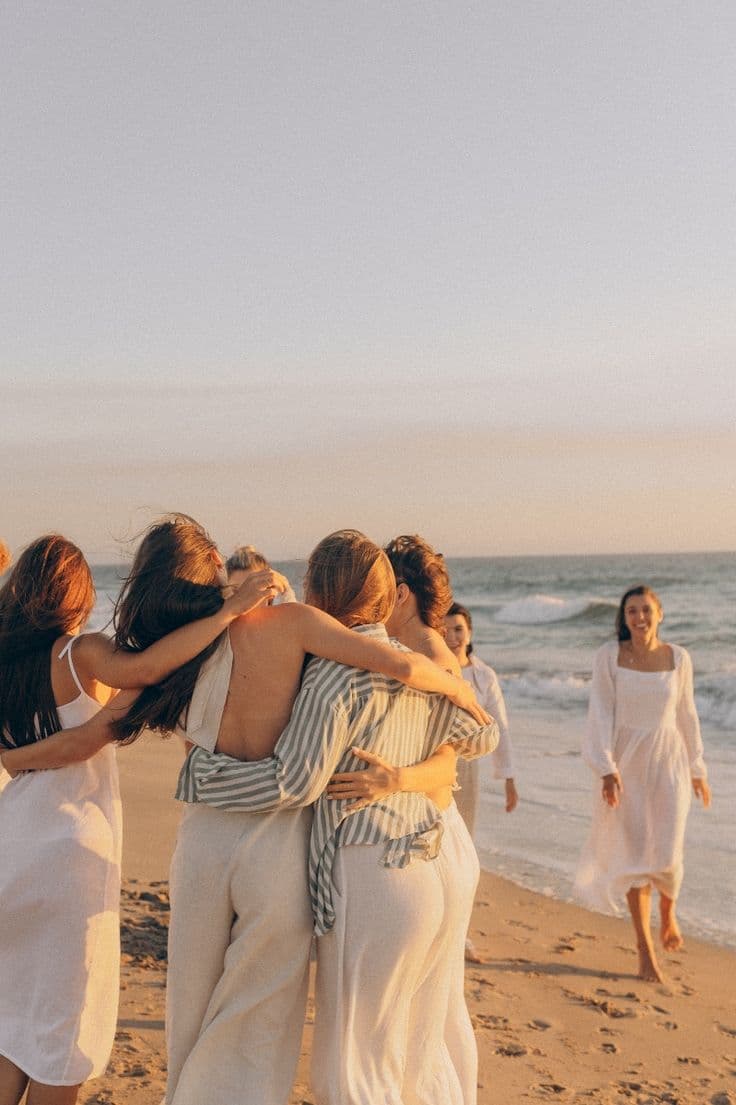Grupo de mujeres abrazándose en la playa al atardecer